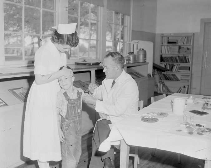 A physician and nurse giving the polio vaccine to a child in 1955, the year that the vaccine was first available in the U.S. Courtesy, Joyner Library, ECU